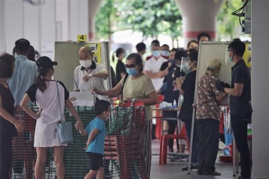 7月10日，人们在新加坡一处投票站戴着手套投票。?